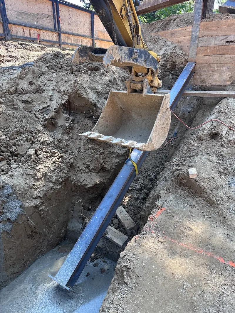Large diagonal steel raker being positioned by excavation equipment