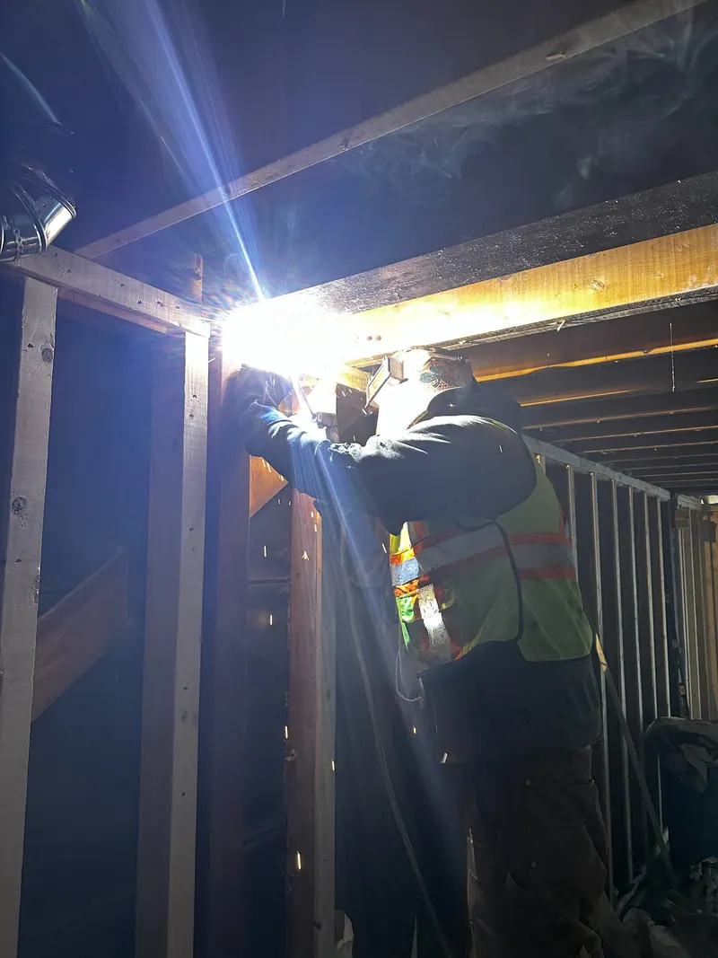 Welder completing an on-site residential structural steel connection