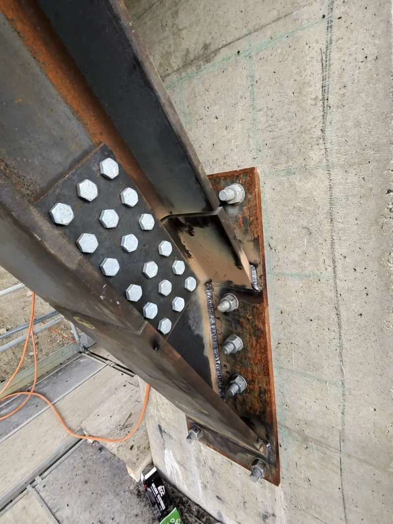 Structural steel connection with bolted splice plates and welded connection steel