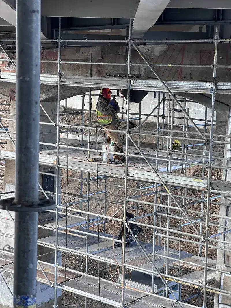 Welder working from scaffolding beneath structural steel